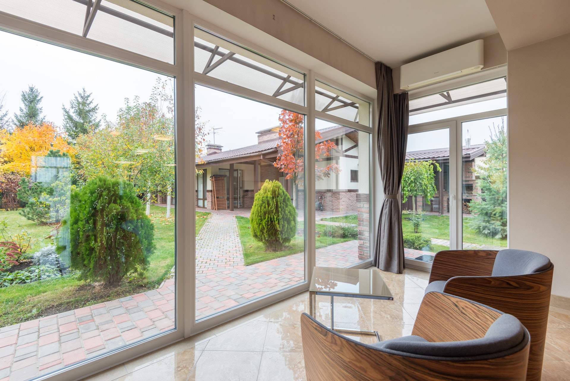 modern home with comfortable armchairs and panoramic windows with view of garden with pathway